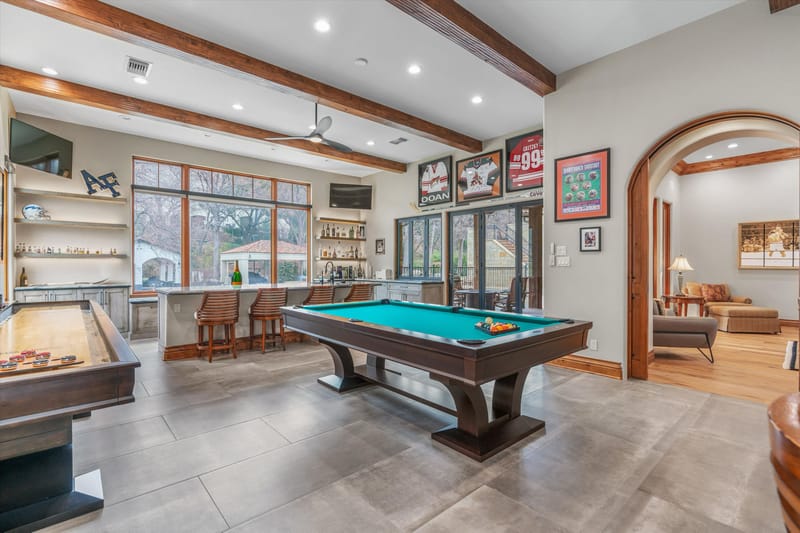 Game and entertainment room with a pool table, shuffleboard, full bar, and sports memorabilia