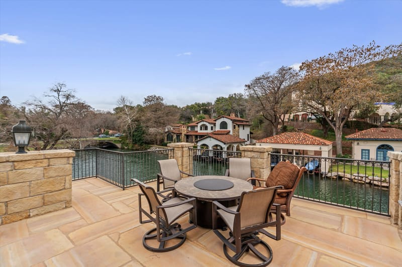 Upper stone terrace with a fire-pit dining table overlooking the Lake Austin canal