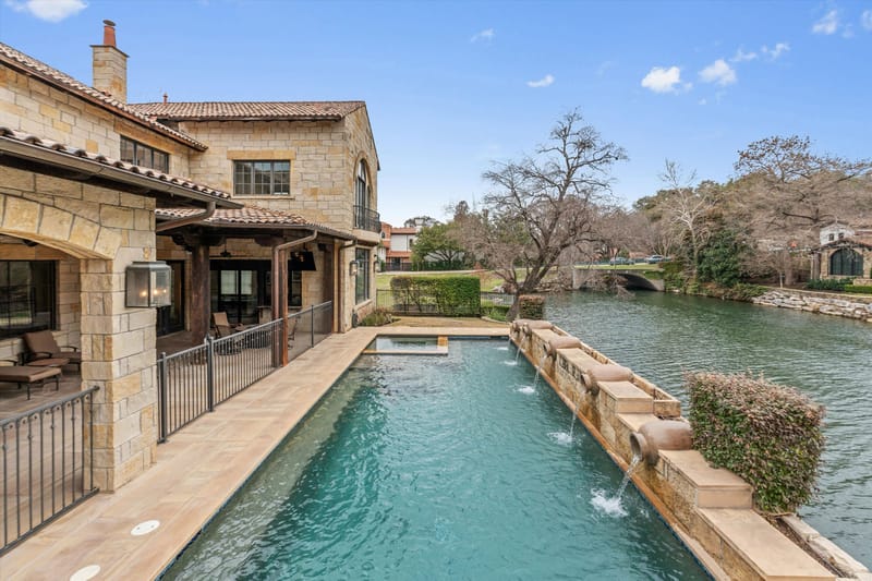 Lap pool and spa beside the lake with cascading stone water features